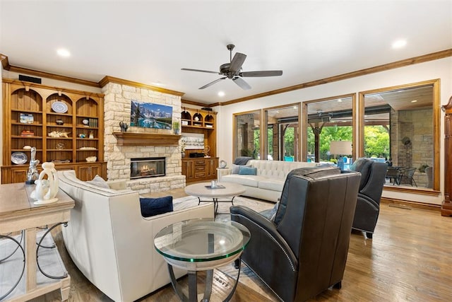1605 Hidden Lake Dr, Edmond, OK 73034 - living area with crown molding, ceiling fan, a stone fireplace, wood finished floors, and built in shelves