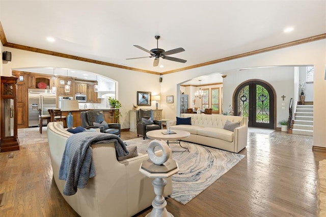 1605 Hidden Lake Dr, Edmond, OK 73034 - living area with arched walkways, ceiling fan, a chandelier, light wood-style floors, and stairway