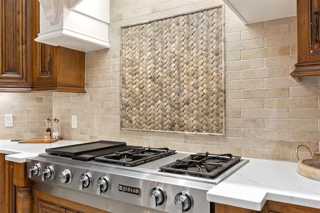1605 Hidden Lake Dr, Edmond, OK 73034 - kitchen featuring stainless steel gas stovetop, brown cabinets, decorative backsplash, and custom range hood