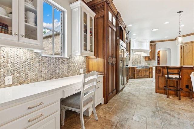 1605 Hidden Lake Dr, Edmond, OK 73034 - kitchen with built in study area, a kitchen bar, stainless steel gas stovetop, glass insert cabinets, and tasteful backsplash