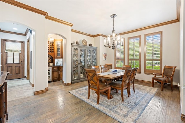 1605 Hidden Lake Dr, Edmond, OK 73034 - dining room featuring arched walkways, a chandelier, ornamental molding, light wood-style floors, and beverage cooler
