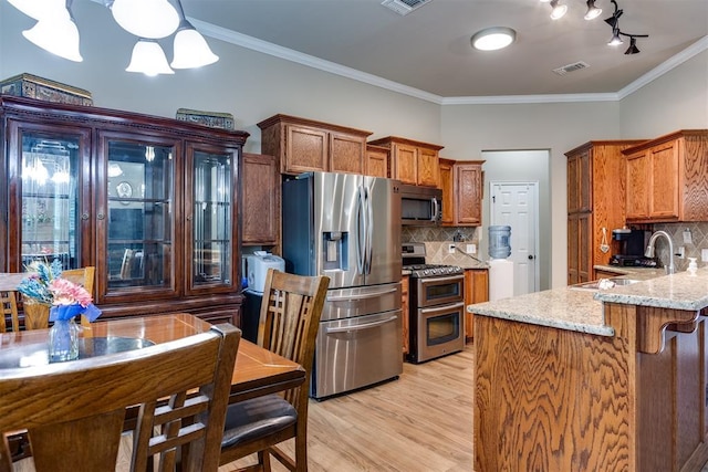 1604 Central Pkwy, Norman, OK 73071 - kitchen with appliances with stainless steel finishes, light wood-style flooring, brown cabinetry, light stone countertops, and tasteful backsplash