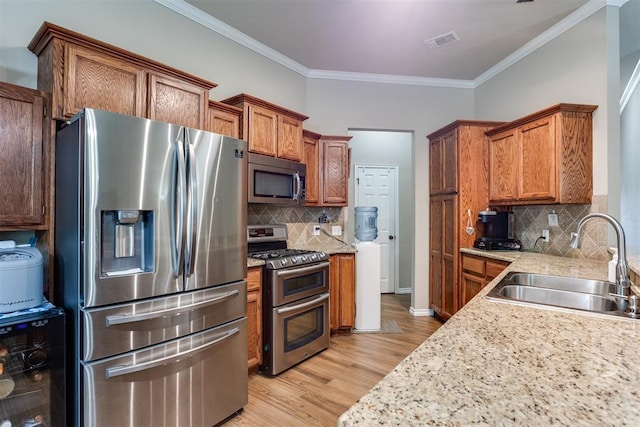 1604 Central Pkwy, Norman, OK 73071 - kitchen featuring stainless steel appliances, beverage cooler, brown cabinets, crown molding, and light wood finished floors