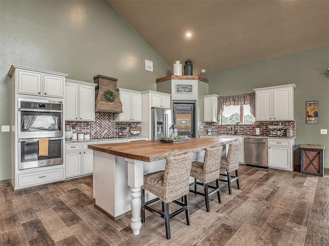 4920 W Forrest Hills Rd, Guthrie, OK 73044 - kitchen with stainless steel appliances, butcher block countertops, dark wood-style floors, decorative backsplash, and high vaulted ceiling