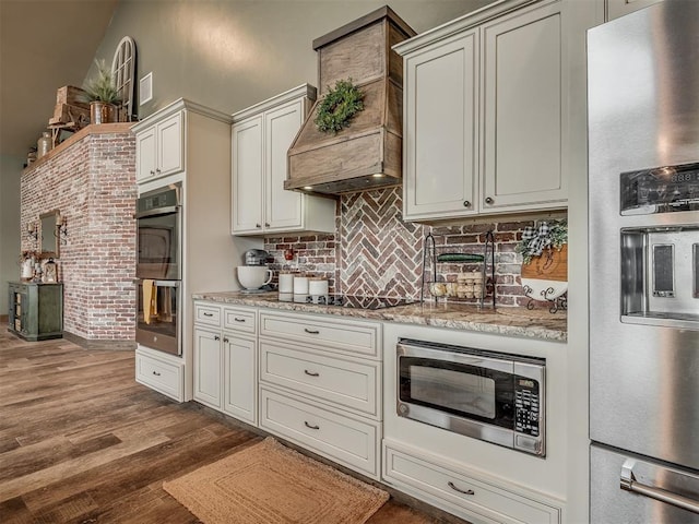 4920 W Forrest Hills Rd, Guthrie, OK 73044 - kitchen with stainless steel appliances, dark wood-style flooring, backsplash, light stone countertops, and custom exhaust hood