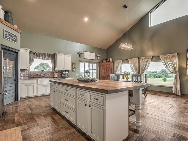 4920 W Forrest Hills Rd, Guthrie, OK 73044 - kitchen featuring butcher block counters, high vaulted ceiling, white cabinetry, a kitchen bar, and a kitchen island