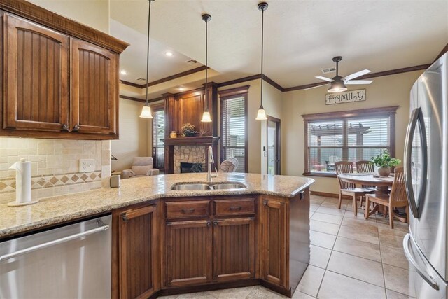 12816 NW 6th St, Yukon, OK 73099 - kitchen with appliances with stainless steel finishes, ornamental molding, a fireplace, a ceiling fan, and healthy amount of natural light