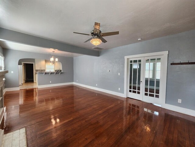 2719 NW 14th St, Oklahoma City, OK 73107 - unfurnished living room featuring french doors, wood-type flooring, ceiling fan, a chandelier, and arched walkways