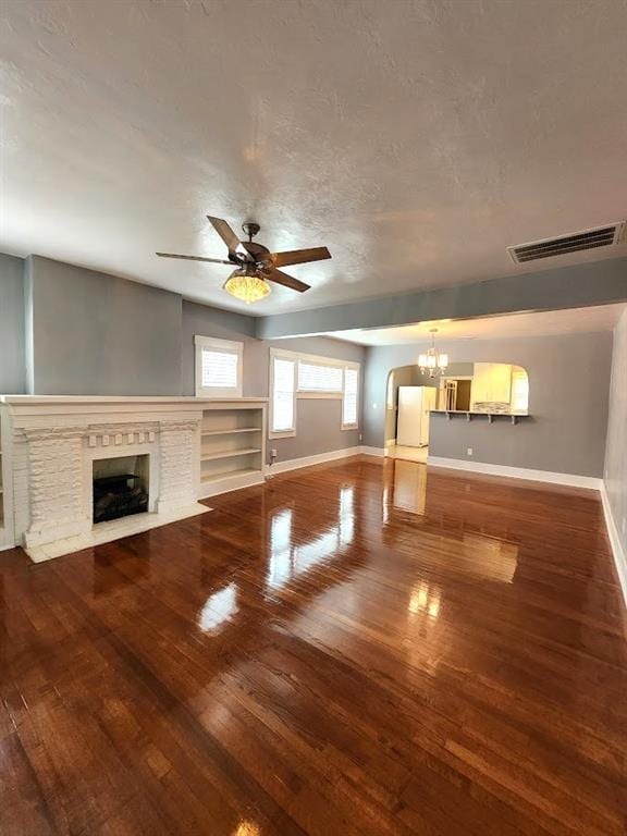 2719 NW 14th St, Oklahoma City, OK 73107 - unfurnished living room featuring a chandelier, wood-type flooring, a fireplace, a ceiling fan, and a textured ceiling