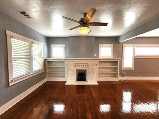 2719 NW 14th St, Oklahoma City, OK 73107 - unfurnished living room with wood-type flooring, a textured ceiling, ceiling fan, and a fireplace with flush hearth