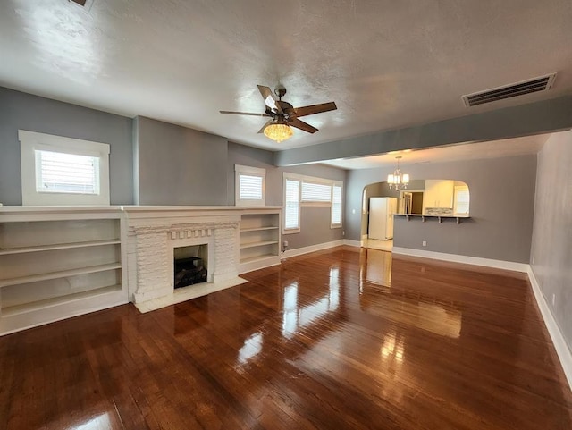 2719 NW 14th St, Oklahoma City, OK 73107 - unfurnished living room featuring a chandelier, wood-type flooring, a ceiling fan, a fireplace with flush hearth, and a textured ceiling