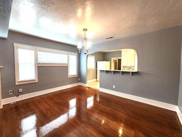 2719 NW 14th St, Oklahoma City, OK 73107 - unfurnished room featuring wood-type flooring, a chandelier, arched walkways, and a textured ceiling