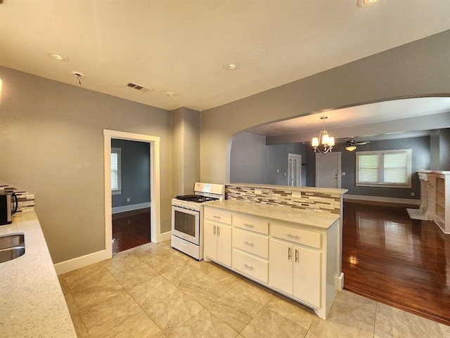 2719 NW 14th St, Oklahoma City, OK 73107 - kitchen featuring white gas range, arched walkways, light countertops, white cabinets, and plenty of natural light