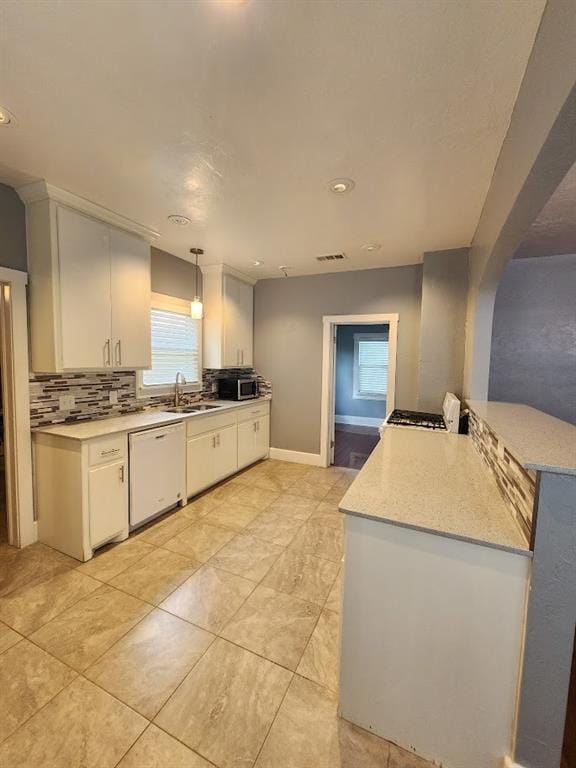 2719 NW 14th St, Oklahoma City, OK 73107 - kitchen featuring white dishwasher, light countertops, plenty of natural light, white cabinets, and recessed lighting