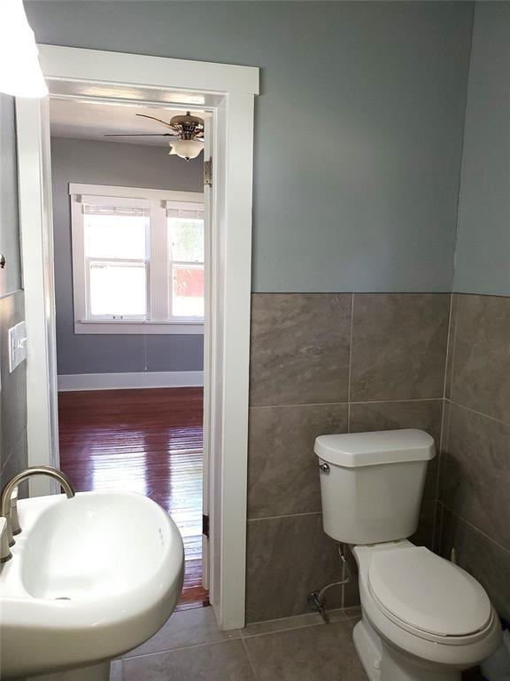 2719 NW 14th St, Oklahoma City, OK 73107 - bathroom featuring tile walls, a ceiling fan, wainscoting, and wood finished floors