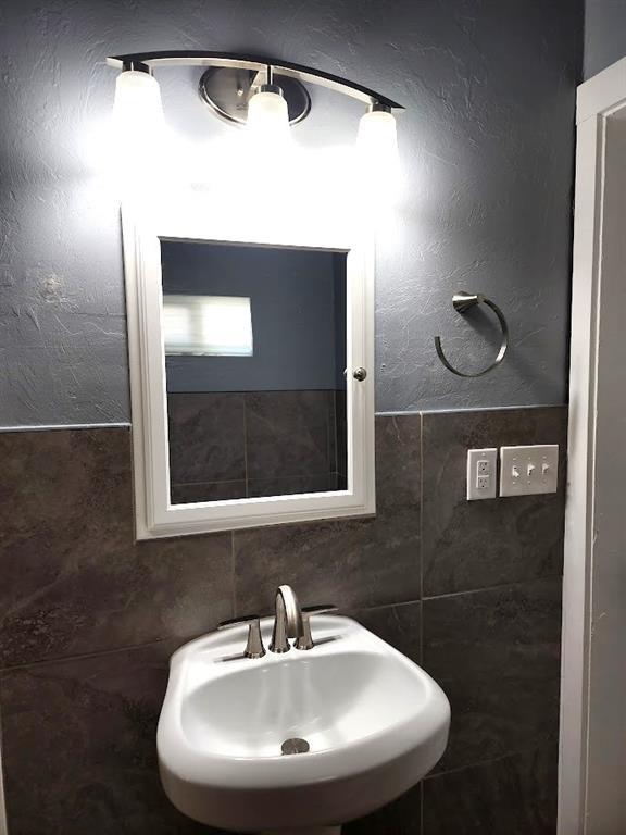 2719 NW 14th St, Oklahoma City, OK 73107 - bathroom featuring a sink and tile walls