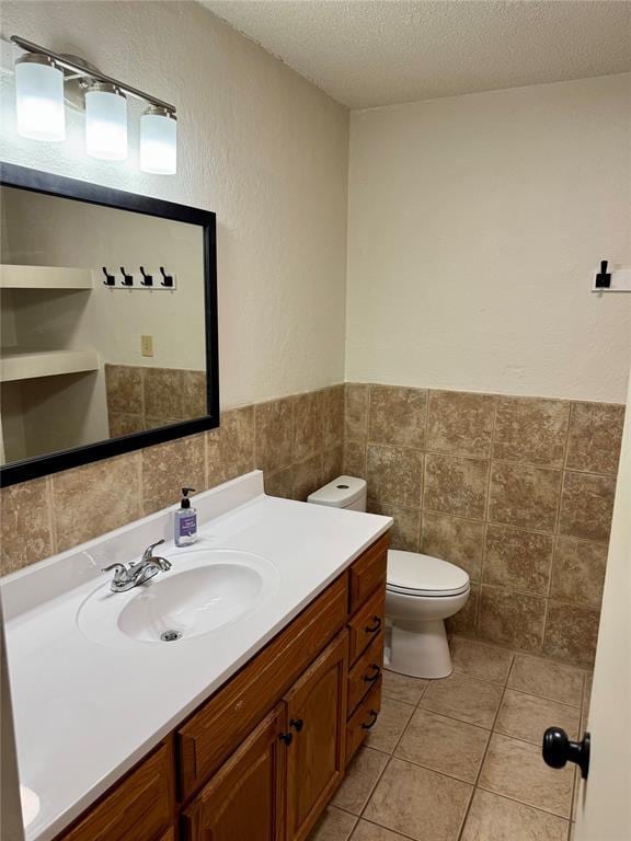 6101 S Douglas Ave, Oklahoma City, OK 73139 - bathroom with tile walls, a textured ceiling, vanity, a wainscoted wall, and tile patterned flooring
