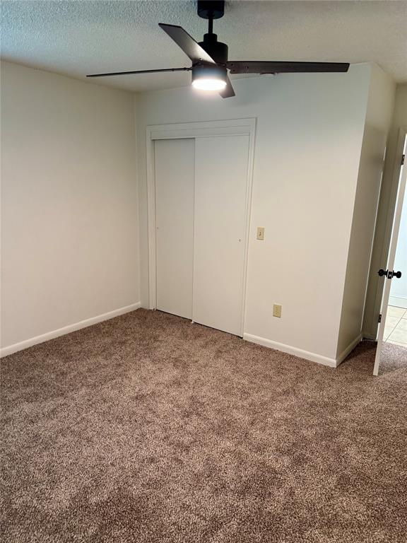 6101 S Douglas Ave, Oklahoma City, OK 73139 - unfurnished bedroom featuring carpet, a closet, a textured ceiling, and ceiling fan