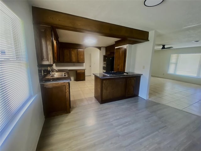 6101 S Douglas Ave, Oklahoma City, OK 73139 - kitchen featuring arched walkways, a ceiling fan, dark countertops, open floor plan, and stainless steel gas stovetop