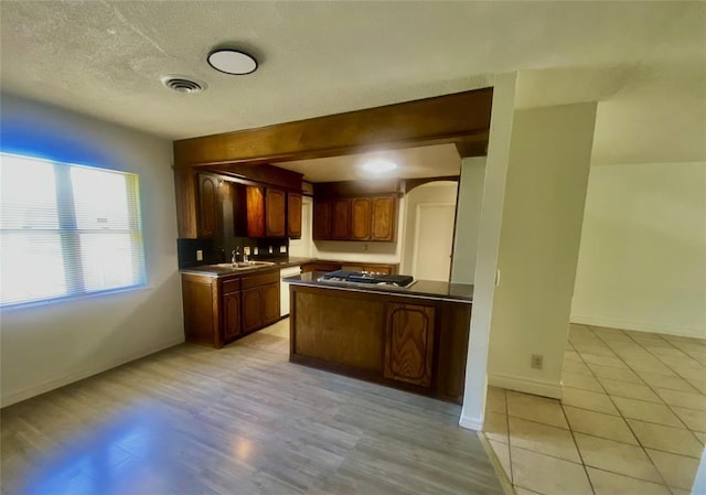 6101 S Douglas Ave, Oklahoma City, OK 73139 - kitchen featuring dishwasher, arched walkways, dark countertops, stainless steel gas cooktop, and light wood-style flooring
