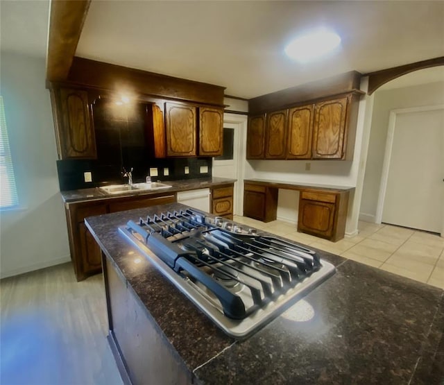 6101 S Douglas Ave, Oklahoma City, OK 73139 - kitchen featuring arched walkways, white dishwasher, stainless steel gas cooktop, dark countertops, and decorative backsplash