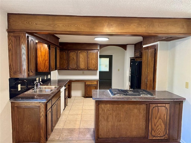 6101 S Douglas Ave, Oklahoma City, OK 73139 - kitchen featuring freestanding refrigerator, arched walkways, a peninsula, stainless steel gas cooktop, and dark countertops