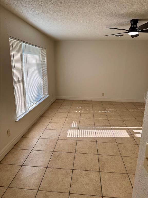 6101 S Douglas Ave, Oklahoma City, OK 73139 - unfurnished room featuring a textured ceiling, healthy amount of natural light, ceiling fan, and light tile patterned flooring