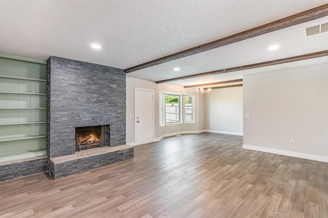 1004 Ranchoak Ct, Yukon, OK 73099 - unfurnished living room with a textured ceiling, a fireplace, wood finished floors, beam ceiling, and a chandelier