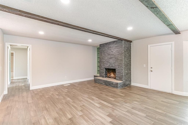 1004 Ranchoak Ct, Yukon, OK 73099 - unfurnished living room featuring a textured ceiling, light wood-style flooring, beamed ceiling, a fireplace, and recessed lighting