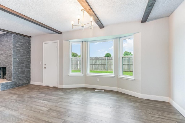 1004 Ranchoak Ct, Yukon, OK 73099 - unfurnished living room with beam ceiling, a textured ceiling, a chandelier, wood finished floors, and a fireplace