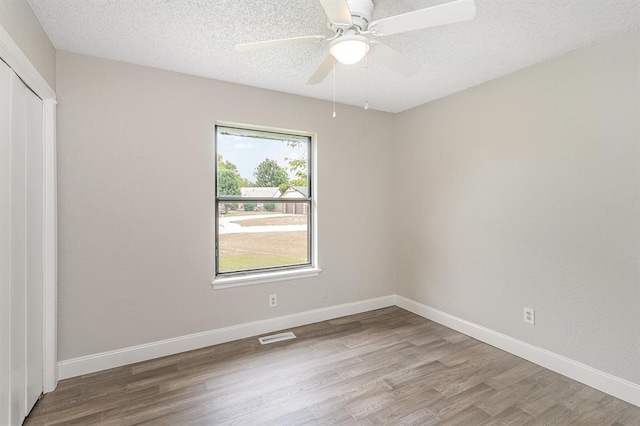 1004 Ranchoak Ct, Yukon, OK 73099 - unfurnished bedroom with wood finished floors, a closet, a textured ceiling, and a ceiling fan
