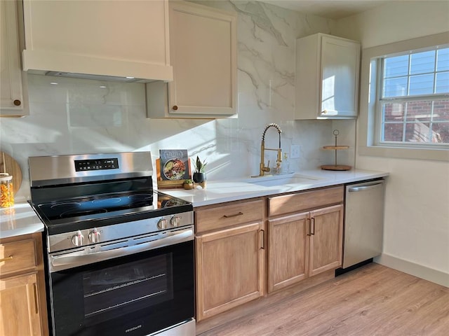 2332 NW 31st St, Oklahoma City, OK 73112 - kitchen featuring appliances with stainless steel finishes, light wood finished floors, light countertops, and premium range hood