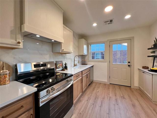 2332 NW 31st St, Oklahoma City, OK 73112 - kitchen featuring appliances with stainless steel finishes, light wood-style flooring, tasteful backsplash, light countertops, and premium range hood