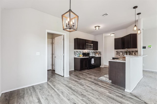 1016 N Deer Court Way, Mustang, OK 73064 - kitchen with black range, stainless steel microwave, tasteful backsplash, dark brown cabinetry, and vaulted ceiling