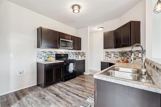 1016 N Deer Court Way, Mustang, OK 73064 - kitchen featuring stainless steel microwave, black gas range oven, dark brown cabinets, light countertops, and tasteful backsplash