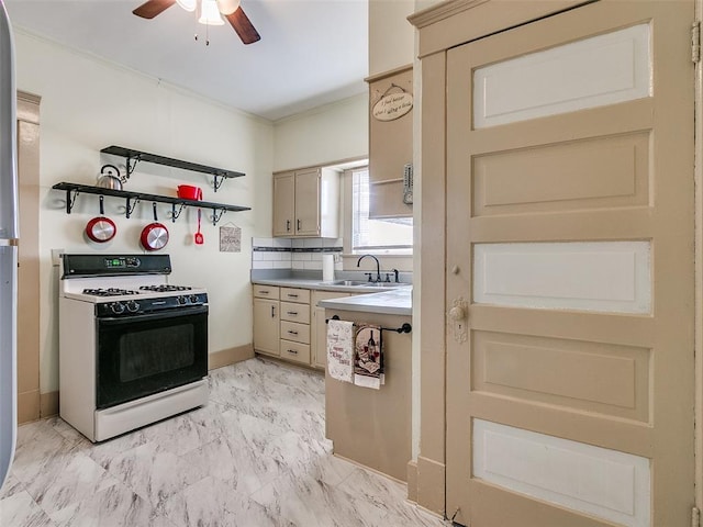 312 NW 24th St, Oklahoma City, OK 73103 - kitchen featuring gas range, ceiling fan, light countertops, light marble finish flooring, and cream cabinetry