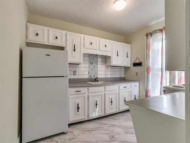 312 NW 24th St, Oklahoma City, OK 73103 - kitchen featuring freestanding refrigerator, light marble finish flooring, white cabinets, decorative backsplash, and light countertops