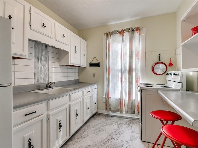 312 NW 24th St, Oklahoma City, OK 73103 - kitchen featuring white appliances, light marble finish floors, white cabinets, backsplash, and light countertops