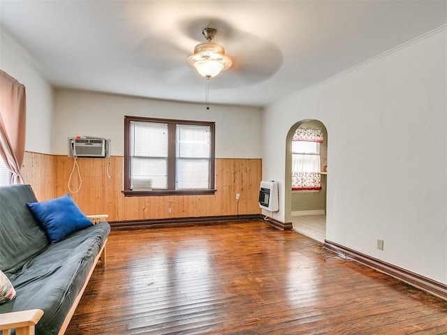312 NW 24th St, Oklahoma City, OK 73103 - unfurnished living room featuring heating unit, an AC wall unit, arched walkways, wood-type flooring, and wainscoting