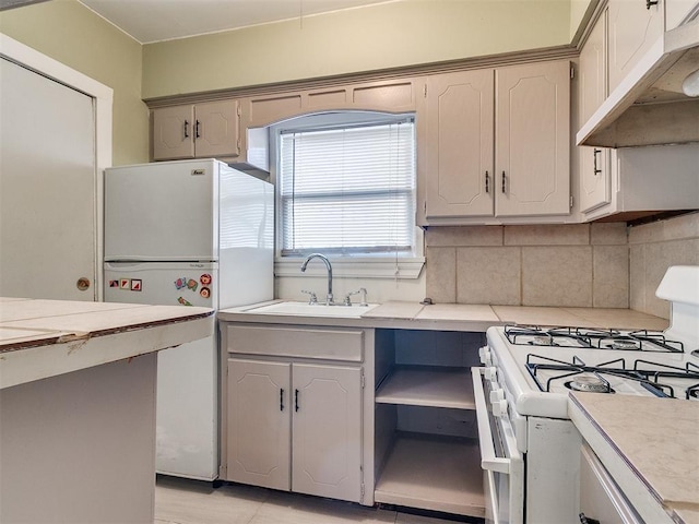 312 NW 24th St, Oklahoma City, OK 73103 - kitchen with white appliances, under cabinet range hood, light countertops, and decorative backsplash