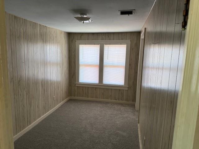 unfurnished room with wood walls and carpet floors