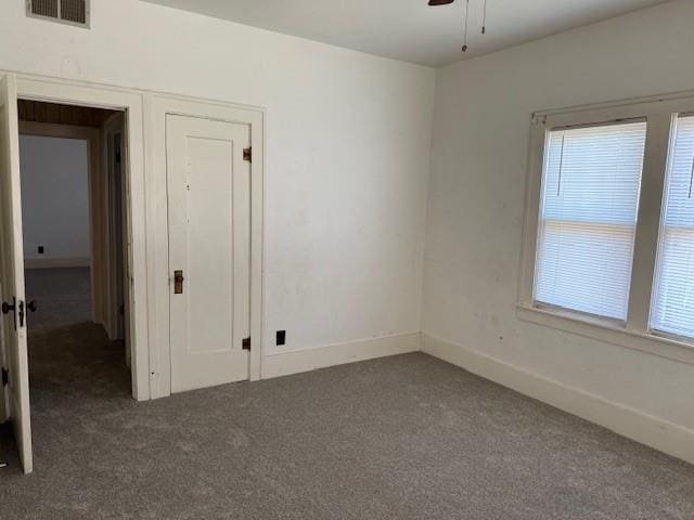 carpeted spare room with a ceiling fan and baseboards