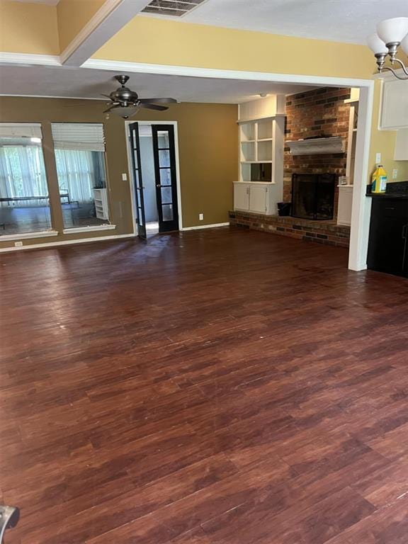 3908 Southwestern Ave, Edmond, OK 73034 - unfurnished living room featuring a fireplace, dark wood finished floors, a ceiling fan, and a chandelier