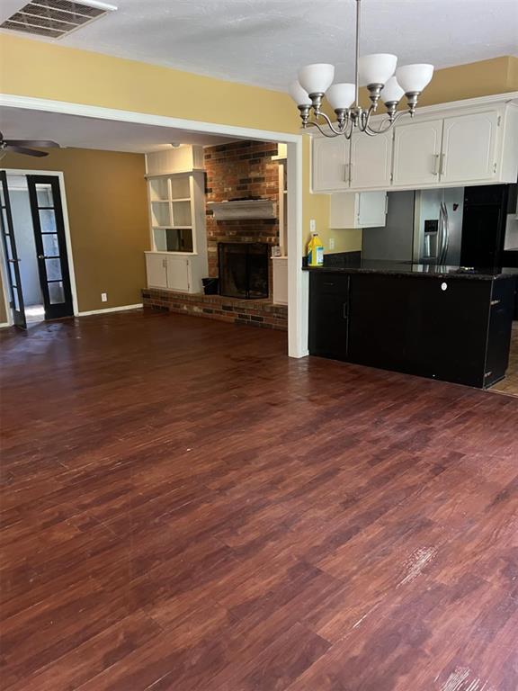 3908 Southwestern Ave, Edmond, OK 73034 - unfurnished living room featuring dark wood-style floors, a fireplace, a chandelier, and ceiling fan