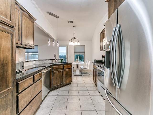 19940 Vivace Ct, Edmond, OK 73013 - kitchen with appliances with stainless steel finishes, vaulted ceiling, decorative backsplash, pendant lighting, and light tile patterned floors