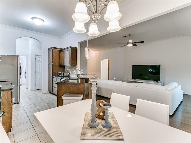 19940 Vivace Ct, Edmond, OK 73013 - dining area with arched walkways, ornamental molding, ceiling fan, light tile patterned floors, and a chandelier