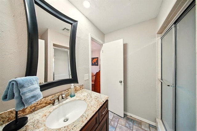 7617 N Ann Arbor Ave, Oklahoma City, OK 73132 - ensuite bathroom featuring stone finish floors, vanity, a stall shower, and a textured wall