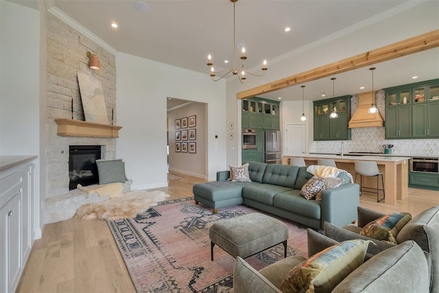 3824 Library Ln, Edmond, OK 73034 - living room featuring ornamental molding, a chandelier, light wood-style flooring, a stone fireplace, and recessed lighting