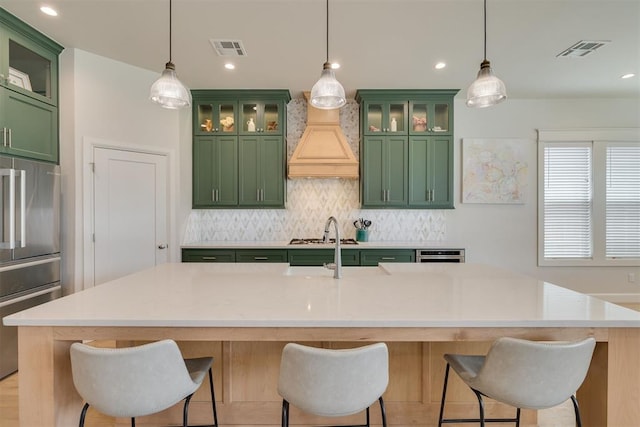 3824 Library Ln, Edmond, OK 73034 - kitchen with green cabinets, backsplash, custom range hood, a center island with sink, and recessed lighting