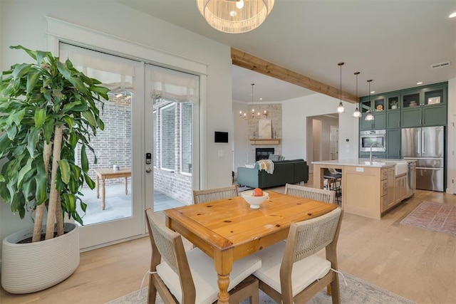 3824 Library Ln, Edmond, OK 73034 - dining space with light wood finished floors, a chandelier, a fireplace, french doors, and recessed lighting